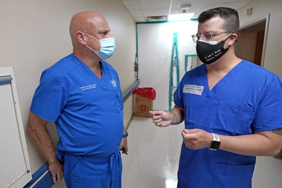 FILE - In this July 16, 2020 file photo, Infectious Disease Physician Army Maj. Gadiel Alvarado, right, with the Urban Augmentation Medical Task Force, talks with United Memorial Medical Center&#039;s Dr. Joseph Varon, inside a newly setup hospital wing in Houston. Texas reported a new daily record for virus deaths Friday and more than 10,000 confirmed cases for the fourth consecutive day. (AP Photo/David J.