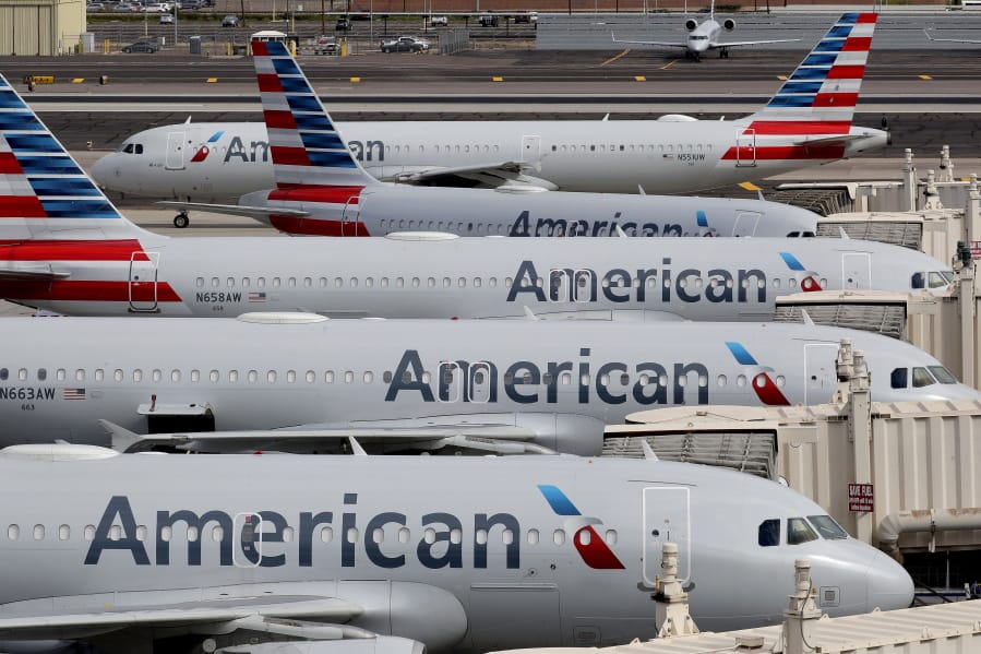 FILE - In this Wednesday, March 25, 2020, file photo, American Airlines jets sit idly at their gates as a jet arrives at Sky Harbor International Airport in Phoenix. American Airlines and four smaller carriers have reached agreement with the government for billions more in federal loans, a sign of the industry&#039;s desperate fight to survive a downturn in air travel caused by the virus pandemic. The Treasury Department said Thursday, July 2, 2020, that it had finalized terms of new loans to American, Spirit Airlines, Frontier Airlines, Hawaiian Airlines and SkyWest Airlines.