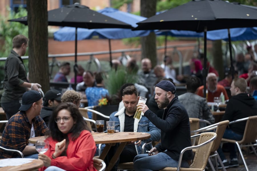 Members of the public are seen at a bar on Canal Street in Manchester&#039;s gay village, England, Saturday July 4, 2020. England is embarking on perhaps its biggest lockdown easing yet as pubs and restaurants have the right to reopen for the first time in more than three months. In addition to the reopening of much of the hospitality sector, couples can tie the knot once again, while many of those who have had enough of their lockdown hair can finally get a trim.