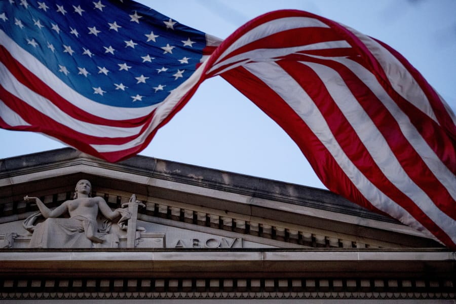 FILE - In this March 22, 2019 file photo, an American flag flies outside the Department of Justice in Washington. The Justice Department has accused two Chinese hackers of stealing hundreds of millions of dollars of trade secrets from companies across the world and more recently targeting firms developing a vaccine for the coronavirus. Officials expected to discuss the indictment at a news conference Tuesday.