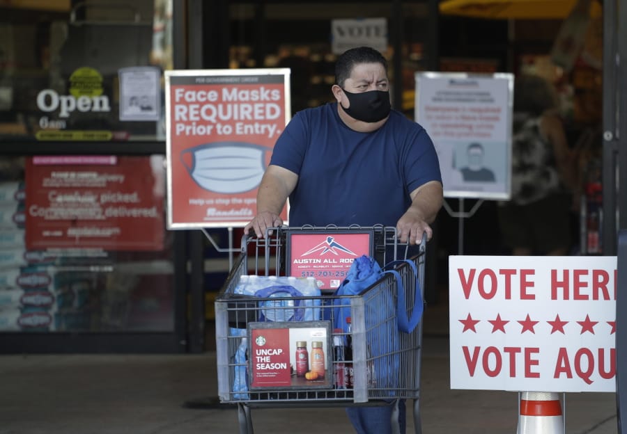 A shopper wearing a mask for protection against COVID-19 leaves a grocery store that is also serving as an early polling site, Thursday, July 9, 2020, in Austin, Texas.