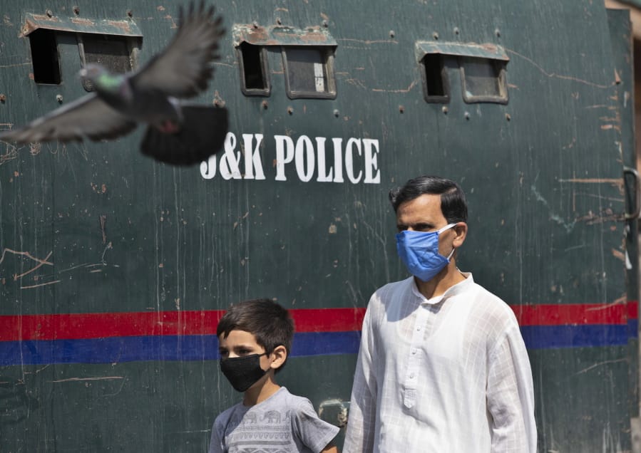 A Kashmiri man and a child wearing masks walk past a parked armored police vehicle in Srinagar, Indian controlled Kashmir, Monday, July 13, 2020. Authorities reimposed lockdown on Monday in parts of Indian-controlled Kashmir, including the region&#039;s main city, following surge in coronavirus cases.