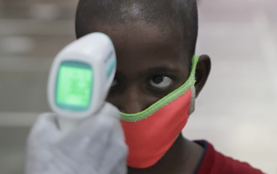 A health worker checks the body temperature of a boy at a medical camp to screen residents for COVID-19 symptoms in Mumbai, India, Friday, July 17, 2020. India crossed 1 million coronavirus cases on Friday, third only to the United States and Brazil, prompting concerns about its readiness to confront an inevitable surge that could overwhelm hospitals and test the country&#039;s feeble health care system.