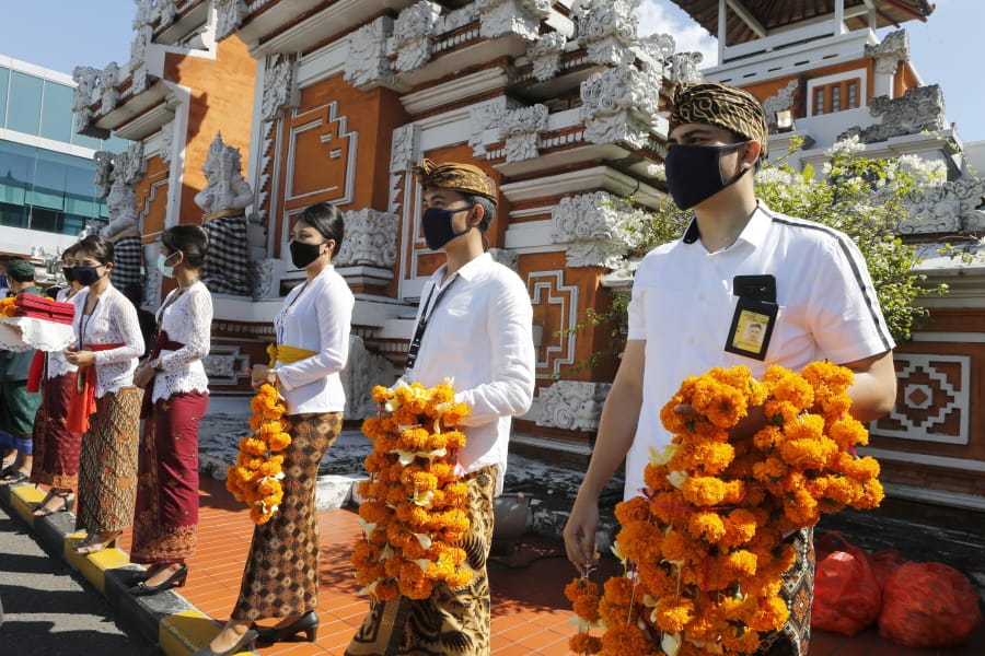 Airport officers wearing face masks line up as they hold flowers to welcome passengers at Bali airport, Indonesia on Friday, July 31, 2020. Indonesia&#039;s resort island of Bali reopened for domestic tourists after months of lockdown due to a new coronavirus.