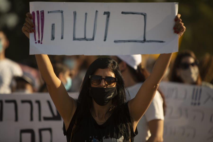 An Israeli social worker holds a sign in Hebrew that reads, &quot;shame,&quot; during a protest against the economic situation in the central Israeli town of Kfar Ahim, Thursday, July 9, 2020. With a new outbreak of coronavirus devastating Israel&#039;s economy, one of Prime Minister Benjamin Netanyahu&#039;s closest confidants was dispatched on to a TV studio on a recent day to calm the nerves of a jittery nation.