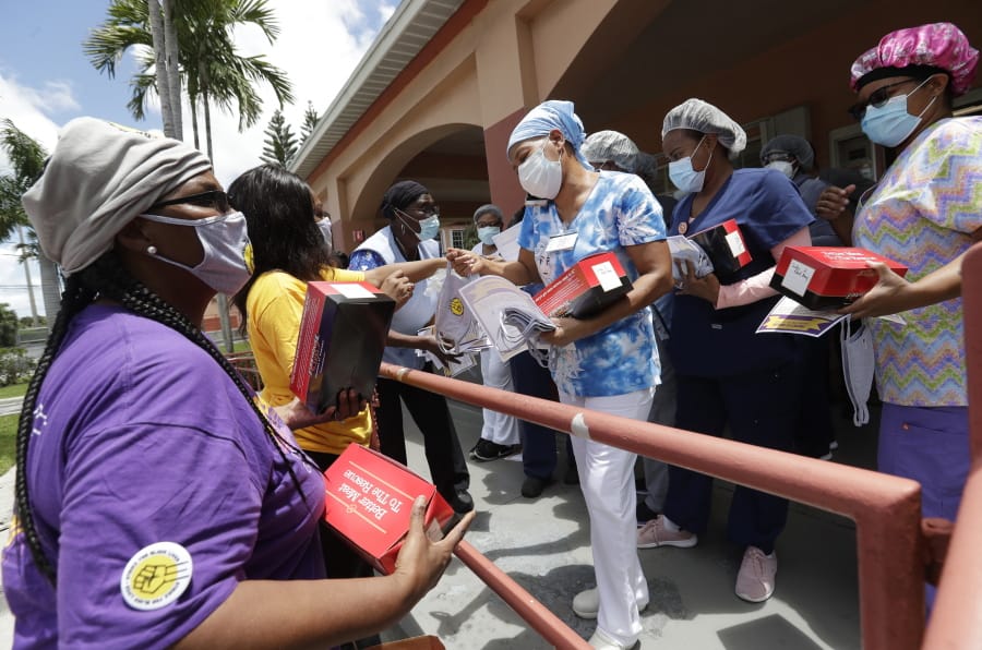 Union members hand out masks to prevent the spread of the new coronavirus and lunches to workers at the Franco Nursing &amp; Rehabilitation Center, Monday, July 20, 2020, in Miami. Most facilities, experts and industry leaders told The Associated Press that a statewide mask mandate would help protect staff members, and consequently residents, from the virus.
