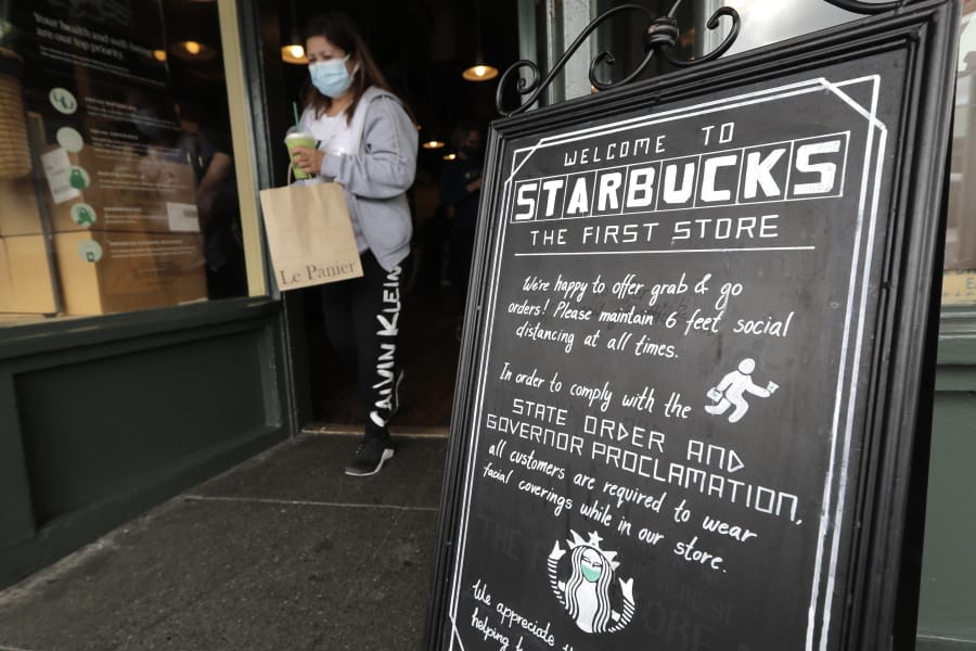 A customer walks out of the first Starbucks store, Tuesday, July 7, 2020, at Pike Place Market in Seattle. Tuesday was the first day of a new statewide order that requires people to wear masks or other facial coverings inside businesses in hopes of slowing the spread of the coronavirus. Business owners who fail to refuse service to customers who don&#039;t wear masks can face fines or lose their business license, but some business owners have raised concerns about turning away customers. (AP Photo/Ted S.