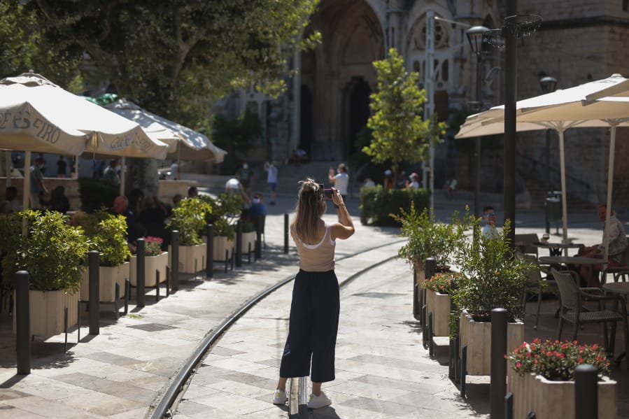 A tourist take photos in town of Soller, in the Balearic Island of Mallorca, Spain, Monday, July 27, 2020. Britain has put Spain back on its unsafe list and announced Saturday that travelers arriving in the U.K. from Spain must now quarantine for 14 days.