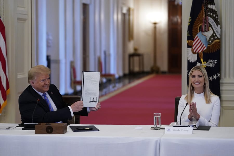 FILE - In this June 26, 2020, file photo, Ivanka Trump, right, applauds as President Donald Trump holds an executive order that he signed during a meeting with the American Workforce Policy Advisory Board, in the East Room of the White House in Washington.