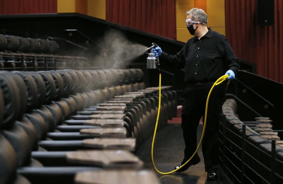 Cinemark West general manager Lindsey Hearn sprays disinfectant on seats in an auditorium the morning before the theater&#039;s June 19 reopening.