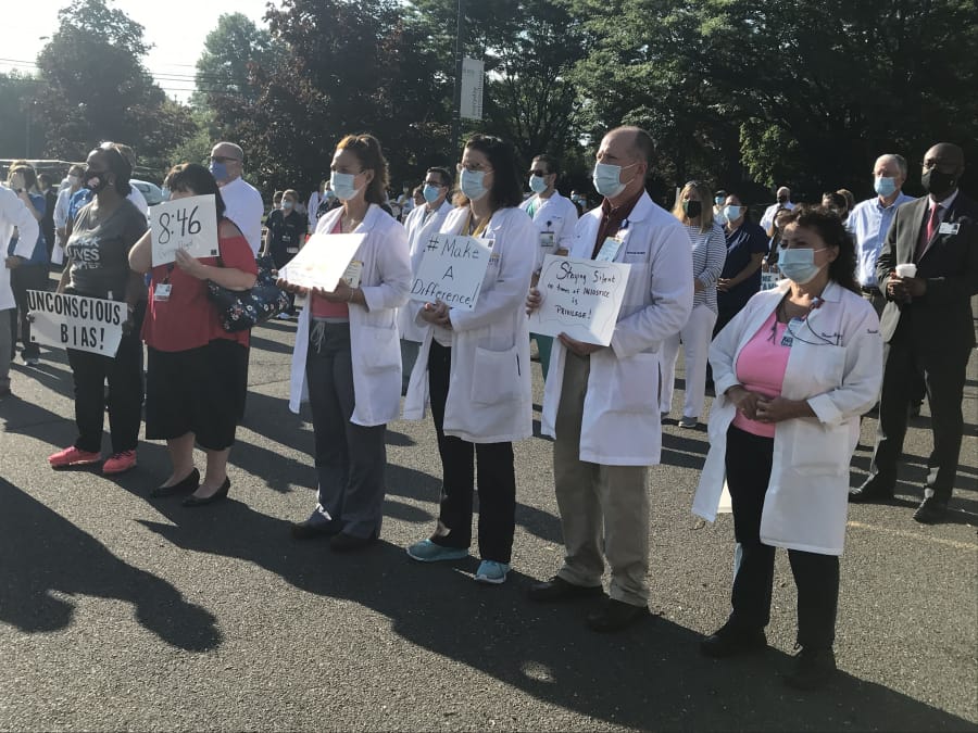 Doctors and other health care workers at Bristol Hospital stand in the &#039;White Coats for Black Lives&#039; event Wednesday.
