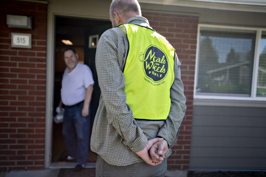 Luepke Center manager Dean Scelza chats with a client, who declined to give their name, while on delivery for Meals on Wheels People in March. Scelza was careful not to shake hands or come too close to those on his delivery route to keep both himself and his clients healthy.