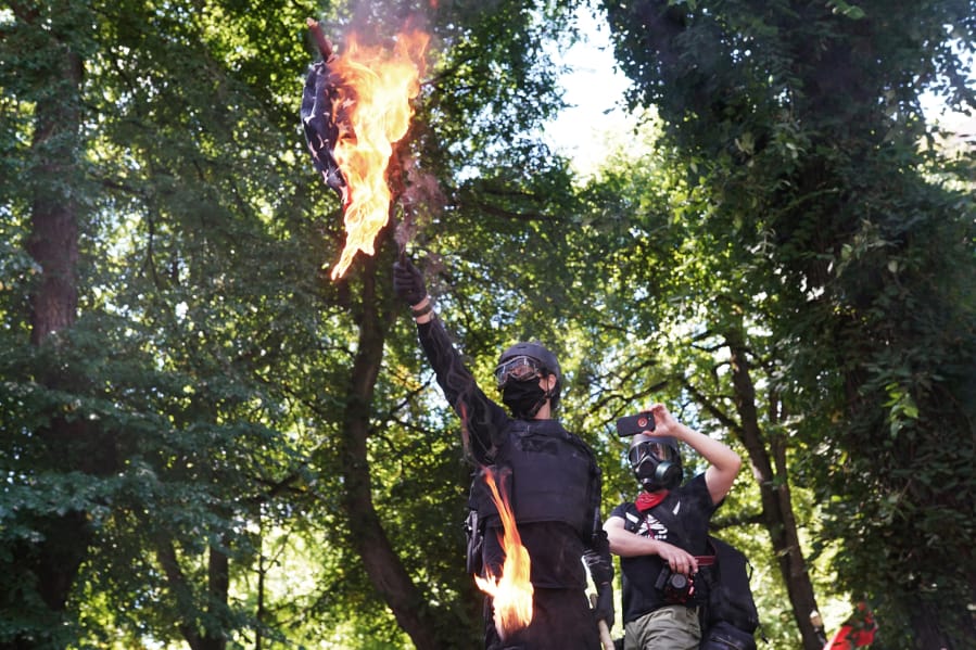 Anti-police protesters burn an American flag while facing off with right wing groups Aug. 22 in front of the Multnomah County Justice Center in Portland.
