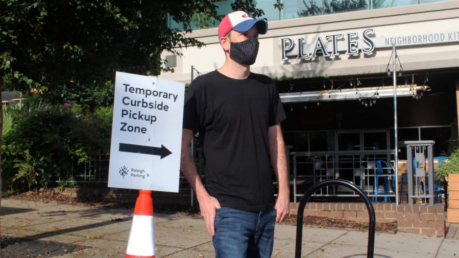 Justin Gallus stands near a curbside pickup zone outside his Plates Neighborhood Kitchen restaurant in downtown Raleigh, North Carolina, this week. Cities and counties are creating these spaces to help keep restaurants in business during the COVID-19 outbreak.