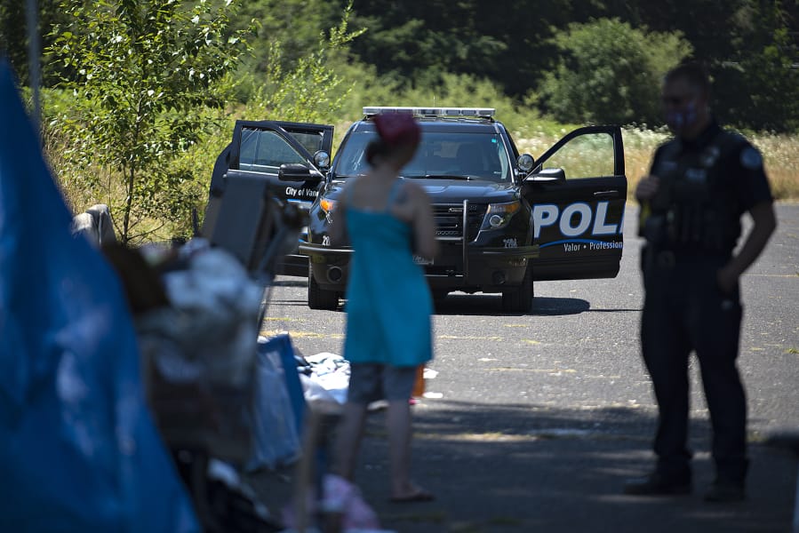 A woman talks with Officer Tyler Chavers as his police vehicle is parked nearby in northeast Vancouver in July.