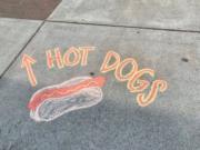 The sidewalk near the Weiner Wagon in Vancouver points the way to hot dogs. The art is by Maria Perez.