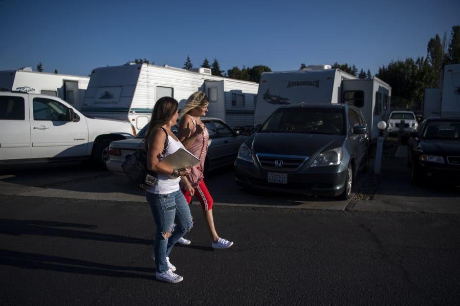 Michele Houston, left, and Cindy Genschorck, right, walk through Hazel Dell RV Park, formerly known as Vancouver RV Park, to talk with tenants about an upcoming online meeting to discuss recent rent increase notices.