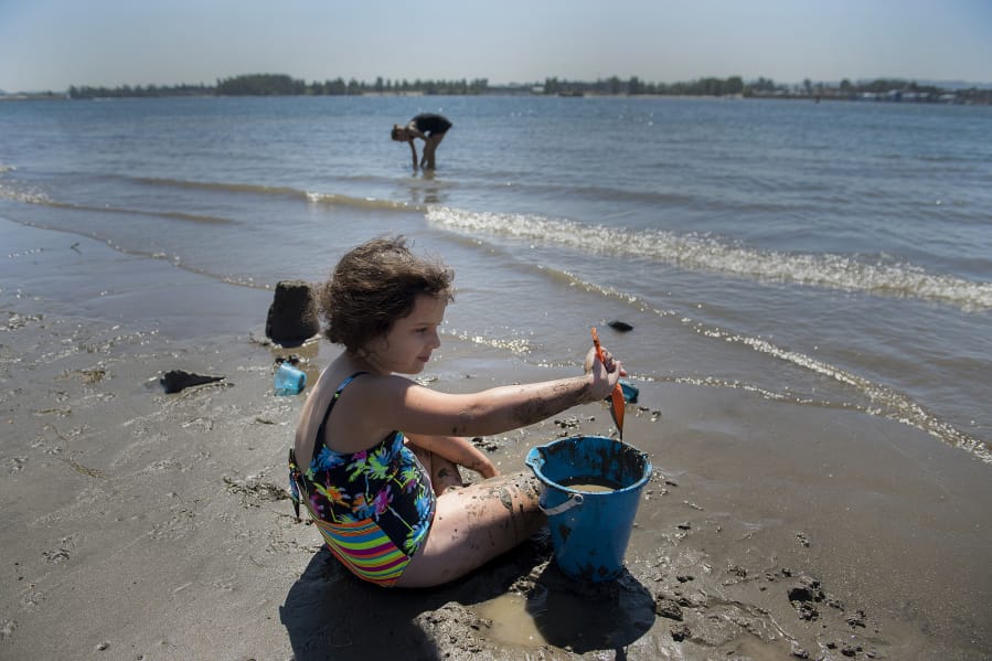 Vancouver resident Heidi Zeigler, 8, cools off in the water while playing in the sand with her mom along the sun-soaked shoreline of the Columbia River on Friday afternoon. Heidi was one of a handful of visitors to the scenic area as residents sought refuge from the high summer temperatures. Forecasts anticipate that high temperatures could reach triple digits over the weekend.