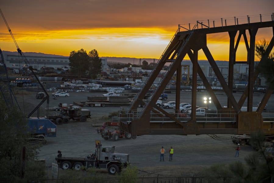The sun sets as crews move the BNSF railroad truss bridge to a barge on Monday evening. The bridge will be floated about 60 miles up the Columbia River to Drano Lake, where it will be installed to replace a century-old bridge on the rail line.