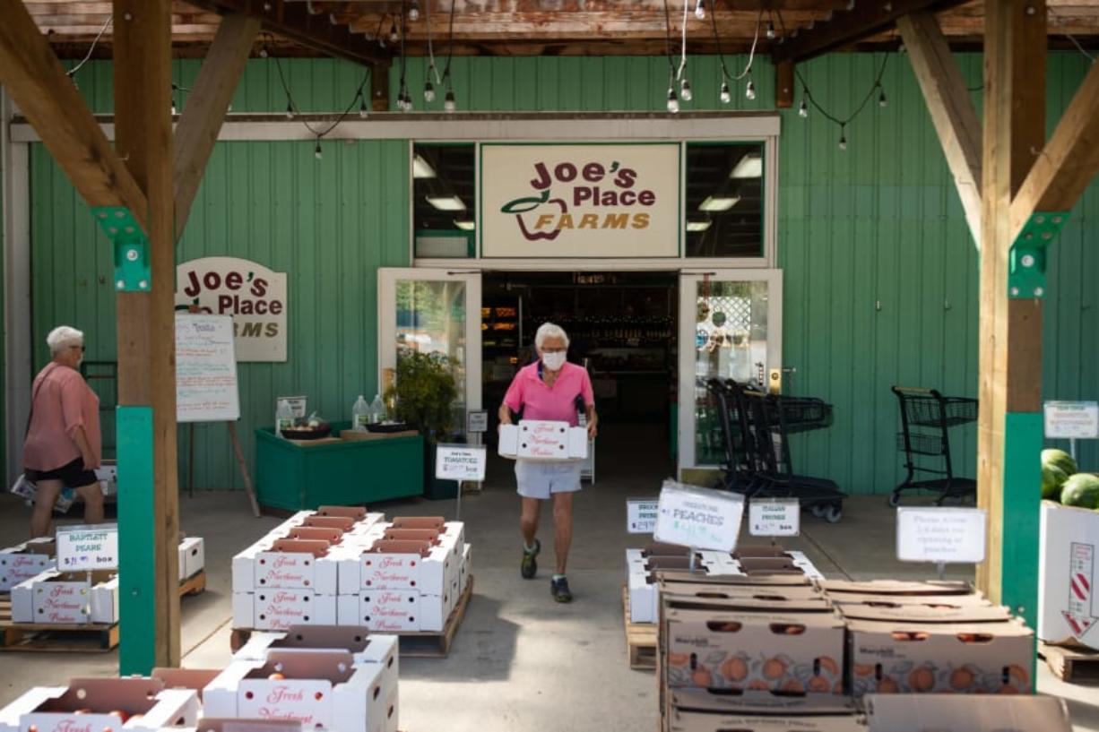 Above, a woman carries a box of produce outside Joe&#039;s Place Farms, which sells more than 25 different fruits and vegetables.