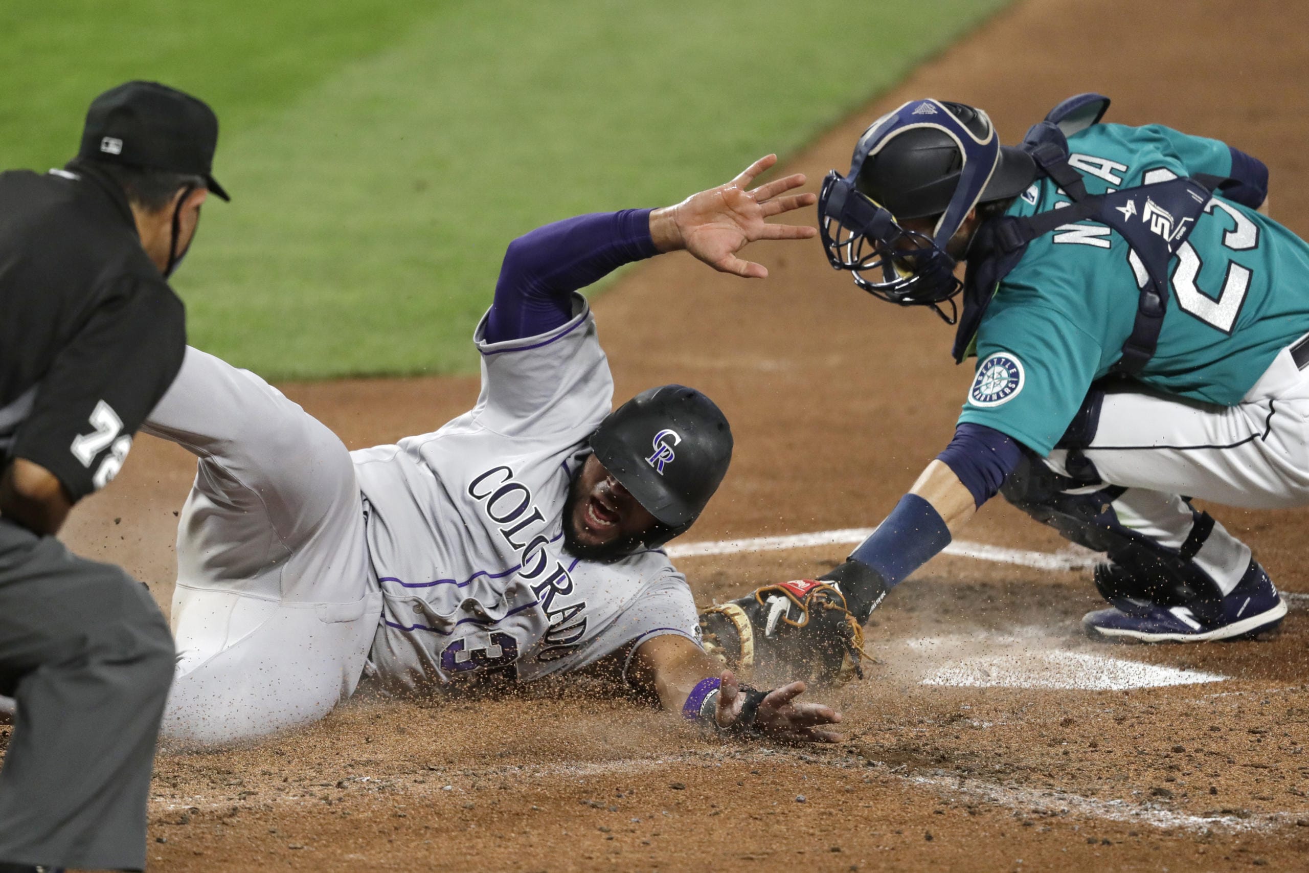 Colorado Rockies' Elias Diaz slides safely across home as Seattle Mariners catcher Austin Nola puts on a late tag in the third inning of a baseball game Friday, Aug. 7, 2020, in Seattle.