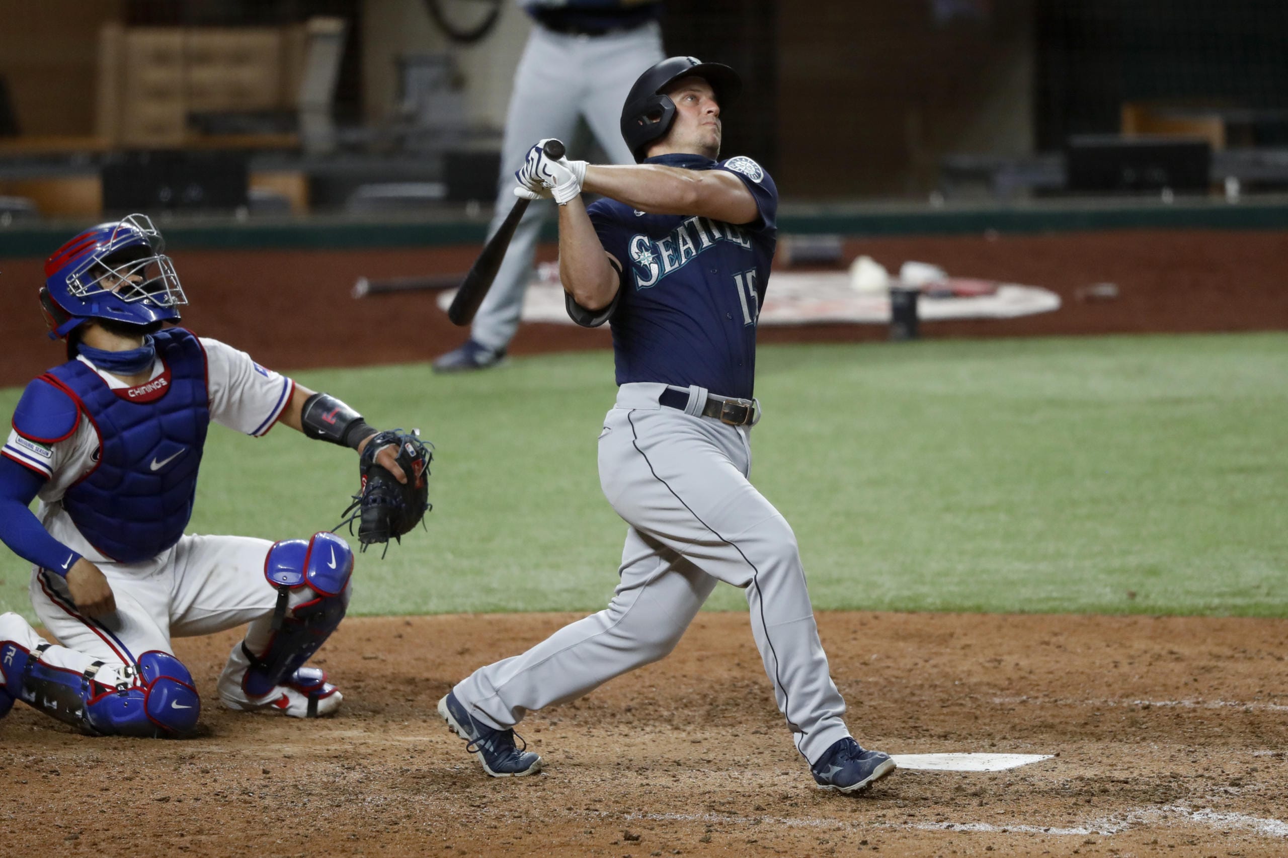 Seattle Mariners' Kyle Seager, right, follows through on a grand slam as Texas Rangers catcher Robinson Chirinos looks on in the sixth inning of a baseball game in Arlington, Texas, Monday, Aug. 10, 2020. The hit also scored Kyle Lewis, Dylan Moore and J.P. Crawford.
