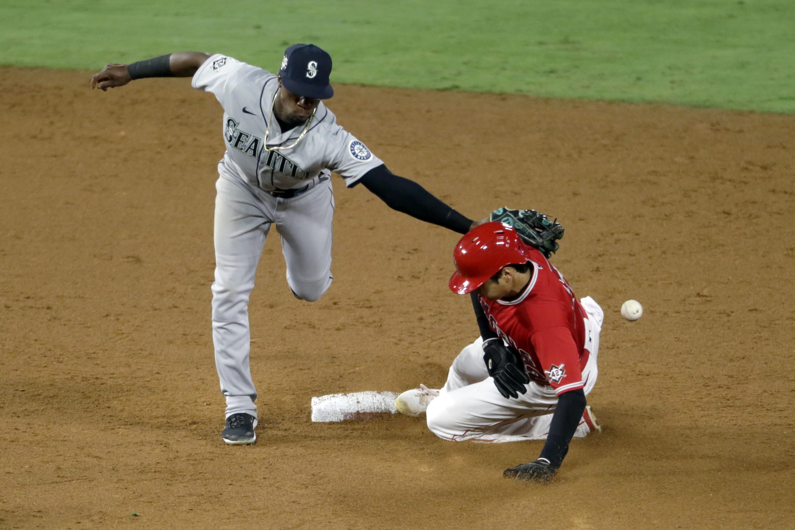 Seattle Mariners second baseman Shed Long Jr., left, misses the ball as Los Angeles Angels' Shohei Ohtani steals second base during the sixth inning of a baseball game in Anaheim, Calif., Friday, Aug. 28, 2020.