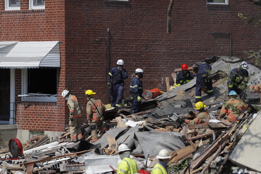 Authorities walk among the piles of debris from an explosion in Baltimore on Monday, Aug. 10, 2020. The &quot;major gas explosion&quot; that involved three houses at Labyrinth and Reistertown roads has left multiple people, including children, trapped according to the Baltimore Fire Department.