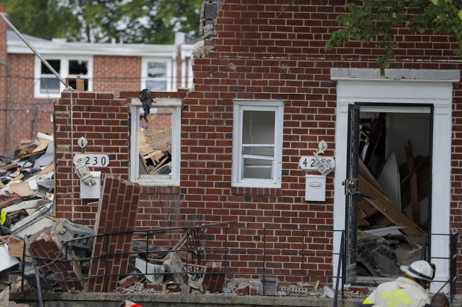 A firefighter walks near the debris in the aftermath of an explosion in Baltimore on Monday, Aug. 10, 2020. Baltimore firefighters say an explosion has leveled several homes in the city.