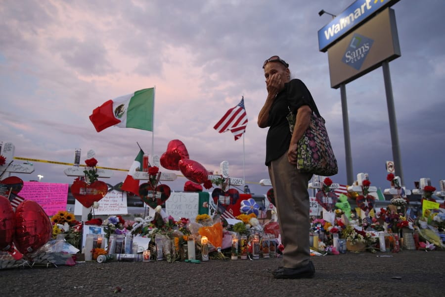 FILE - In this Aug. 6, 2019 file photo, Catalina Saenz wipes tears from her face as she visits a makeshift memorial near the scene of a mass shooting at a shopping complex in El Paso, Texas. El Paso is marking the year anniversary of the a shooting at a crowded Walmart by remembering the 23 people killed. Authorities have said the gunman traveled from his home near Dallas to target Latinos in the Texas border city on Aug. 3, 2019.