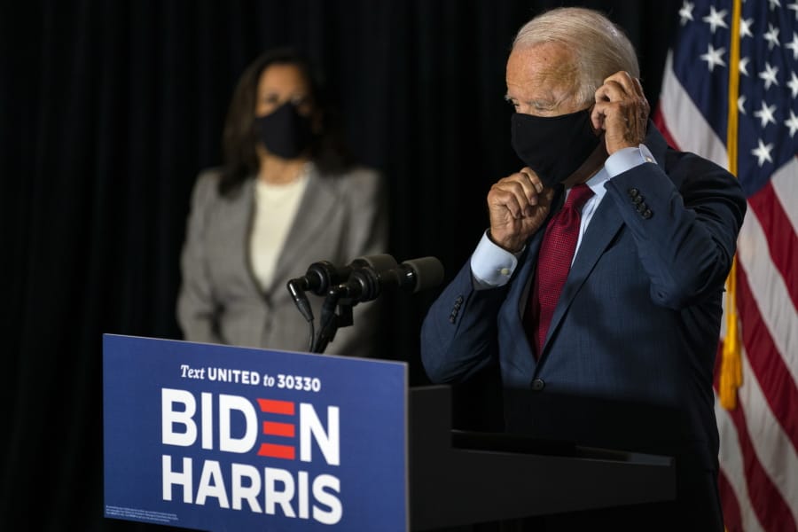 Democratic presidential candidate former Vice President Joe Biden joined by his running mate Sen. Kamala Harris, D-Calif., replaces his face mask after speaking at the Hotel DuPont in Wilmington, Del., Thursday, Aug. 13, 2020.