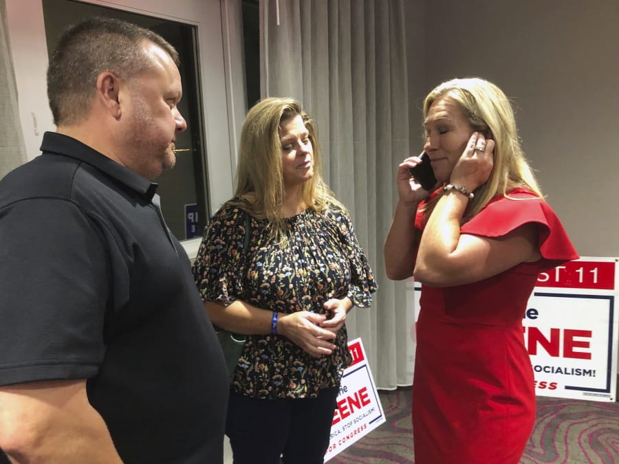 Supporters stand with construction executive Marjorie Taylor Greene, right, as she&#039;s on the phone, late Tuesday, Aug. 11, 2020, in Rome, Ga. Greene, criticized for promoting racist videos and adamantly supporting the far-right QAnon conspiracy theory, won the GOP nomination for northwest Georgia&#039;s 14th Congressional District.