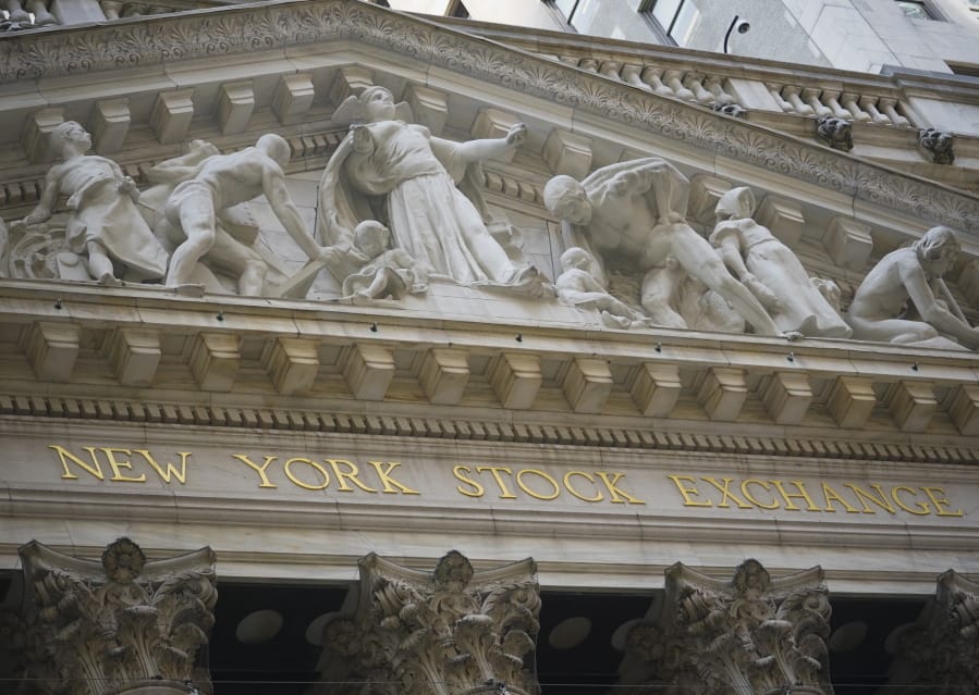 FILE - Marble sculptures occupy the pediment above the New York Stock Exchange signage, Tuesday Aug. 25, 2020, in New York.  Stocks are pushing further into record heights on Wall Street Thursday, after the Federal Reserve made a major overhaul to its strategy, one that could keep interest rates lower for longer.