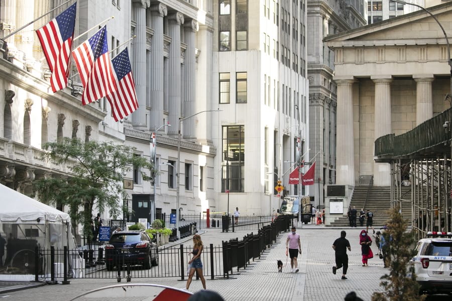 FILE - People walk by the New York Stock Exchange, left, Tuesday, July 21, 2020.  Wall Street is drifting in early trading on Monday, Aug. 10,  after President Donald Trump announced several stopgap moves to aid the economy.