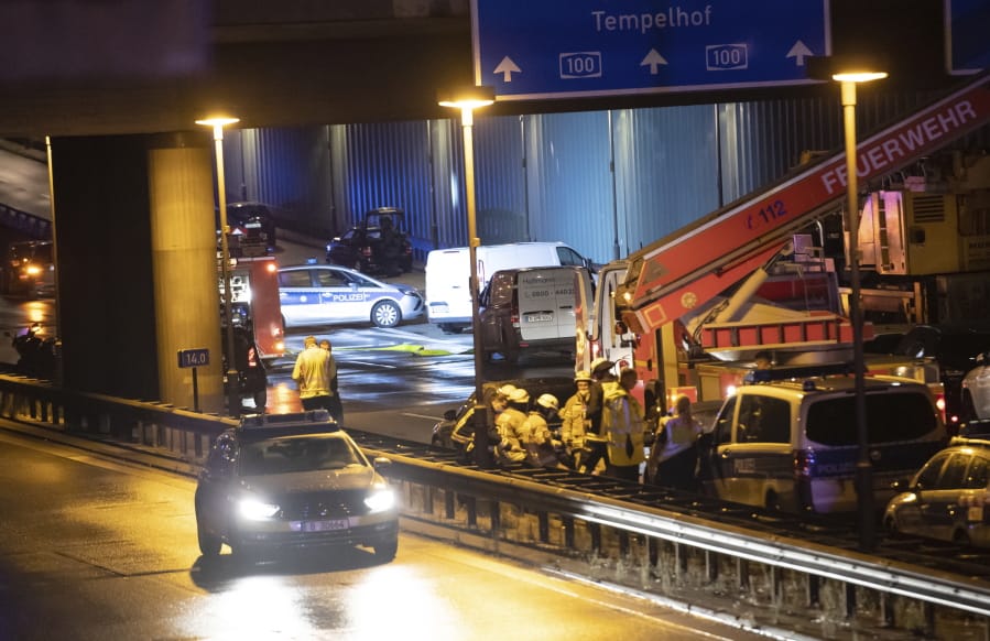 Forensic experts are investigating a car at the city motorway A100 after an accident in Berlin, Germany, Tuesday, Aug. 18, 2020. According to German news agency dpa, prosecutors say the series of crashes caused by a 30-year-old Iraqi man on the highway was an Islamic extremist attack.