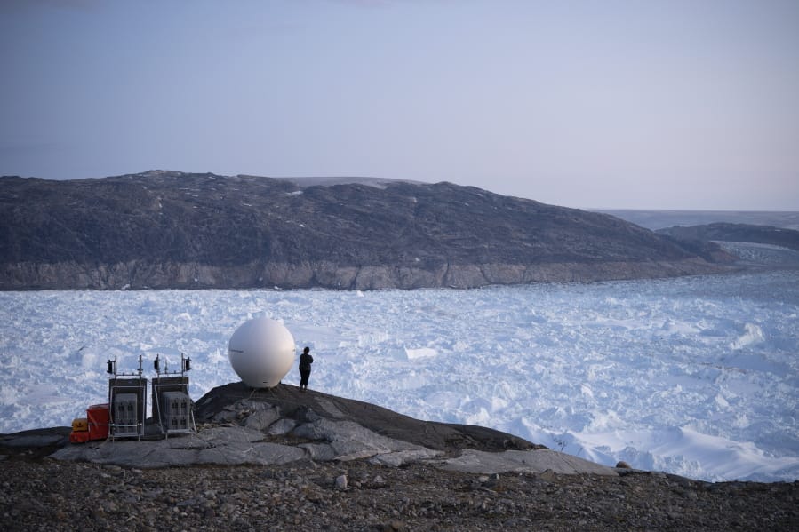 FILE - In this Aug. 16, 2019 file photo, a woman stands next to an antenna at an NYU base camp at the Helheim glacier in Greenland. According to a study released on Thursday, Aug. 20, 2020, Greenland lost a record amount of ice during an extra warm 2019, with the melt massive enough to cover California in more than four feet (1.25 meters) of water.