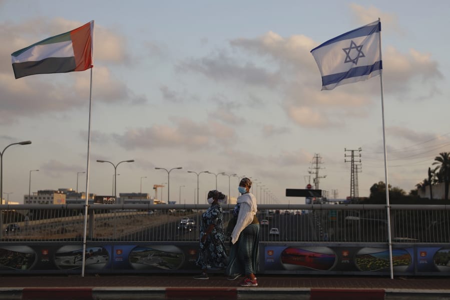 Women wearing face masks against the coronavirus walk past United Arab Emirates and Israeli flags at the Peace Bridge in Netanya, Israel, Sunday, Aug. 16, 2020. The UAE flag was displayed to celebrate last week&#039;s announcement that Israel and the United Arab Emirates have agreed to establish full diplomatic relations.