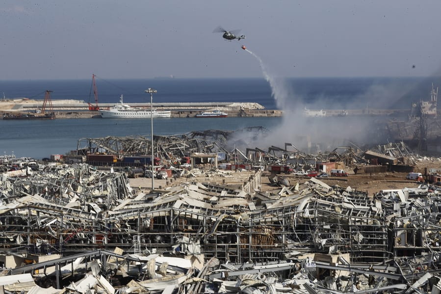 A Lebanese army helicopter throw water at the scene where an explosion hit the seaport of Beirut, Lebanon, Wednesday, Aug. 5, 2020. Residents of Beirut awoke to a scene of utter devastation on Wednesday, a day after a massive explosion at the port sent shock waves across the Lebanese capital, killing at least 100 people and wounding thousands.
