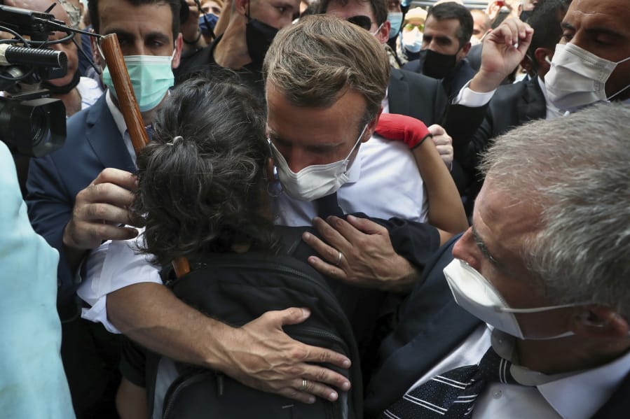 French President Emmanuel Macron, hugs a woman as he visits the Gemayzeh neighborhood, which suffered extensive damage from an explosion on Tuesday that hit the seaport of Beirut, Lebanon, Thursday, Aug. 6, 2020.