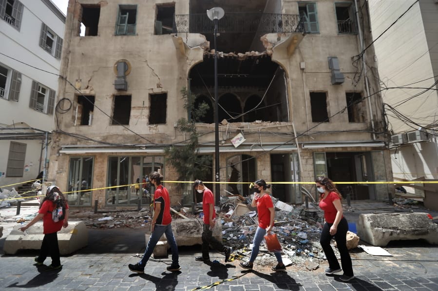 University students who volunteered to help clean damaged homes and give other assistance, pass in front of a building that was damaged by last week&#039;s explosion, in Beirut, Lebanon, Tuesday, Aug. 11, 2020. The explosion that tore through Beirut left around a quarter of a million people with homes unfit to live in. But there are no collective shelters, or people sleeping in public parks. That&#039;s because in the absence of the state, residents of Beirut opened their homes to relatives, friends and neighbors.