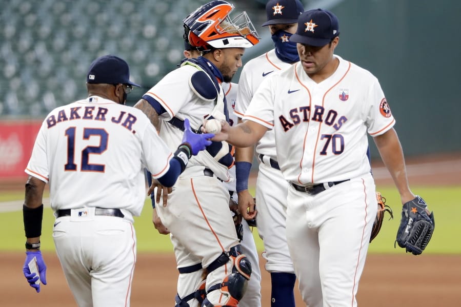 Houston Astros manager Dusty Baker Jr. (12) takes the ball from relief pitcher Andre Scrubb (70) as Scrubb is relieved during the seventh inning of a baseball game against the Seattle Mariners, Sunday, Aug. 16, 2020, in Houston.