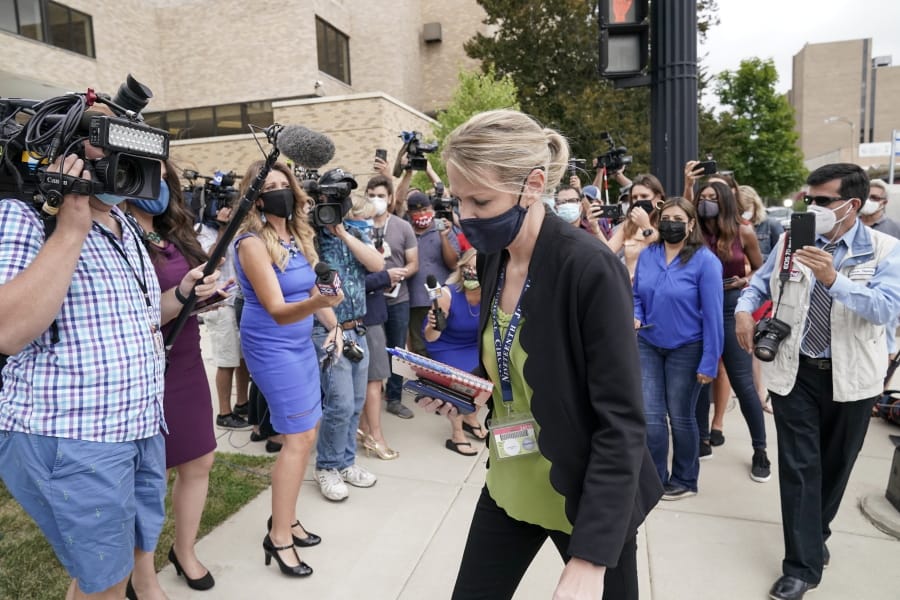 Kasey Morgan, a public information officer for the Lake County Court, walks away from reporters outside the Lake County courthouse following the extradition hearing for Kyle Rittenhouse Friday, Aug. 28, 2020, in Waukegan, Ill. A judge agreed Friday to delay for a month a decision on whether the 17-year-old from Illinois should be returned to Wisconsin to face charges accusing him of fatally shooting two protesters and wounding a third during a night of unrest following the weekend police shooting of Jacob Blake in Kenosha.