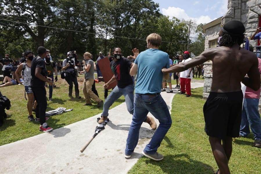 Protesters clash during a demonstration, Saturday, Aug. 15, 2020, in Stone Mountain Village, Ga.  Several dozen people waving Confederate flags, many of them wearing military gear, gathered in downtown Stone Mountain where they faced off against a few hundred counterprotesters, many of whom wore shirts or carried signs expressing support for the Black Lives Matter movement.