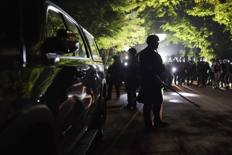 Portland police officers walk through the Laurelhurst neighborhood after dispersing protesters from the Multnomah County Sheriff&#039;s Office early in the morning on Saturday, Aug. 8, 2020 in Portland, Ore.