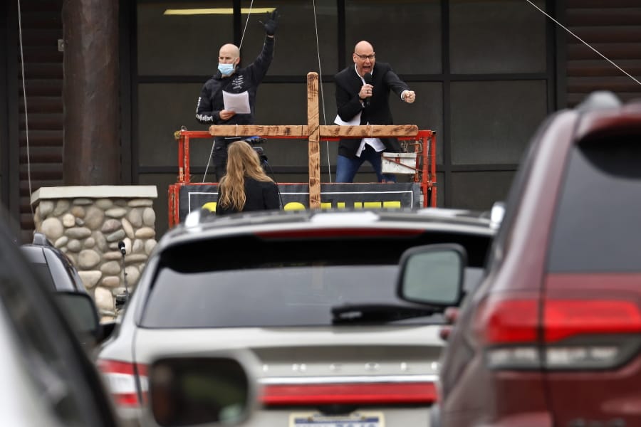FILE - Paster Bruce Schafer, top right, preaches from a scissor lift during the first of two drive-in Easter services held by Grace Life Church in a parking lot in Monroeville, Pa., Sunday, April 12, 2020. The principle of religious freedom is important to most Americans. But as President Donald Trump touts his support for it during his reelection bid, there are notable fault lines among people of different faiths and political ideologies over what it truly means. (AP Photo/Gene J.