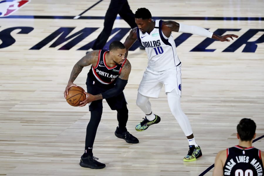 Portland Trail Blazers guard Damian Lillard holds the ball while defended by Dallas Mavericks forward Dorian Finney-Smith (10) during the second half of an NBA basketball game Tuesday, Aug. 11, 2020, in Lake Buena Vista, Fla.