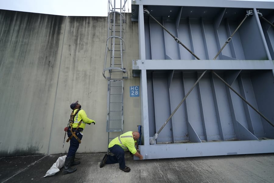 Workers for the Southeast Louisiana Flood Protection Authority - West close floodgates in Harvey, La., just outside New Orleans, Monday, Aug. 24, 2020, in advance of Hurricane Marco, expected to come near the Southern Louisiana coast.