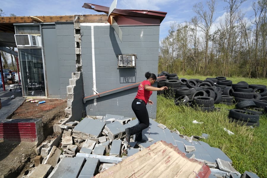 Layla Winbush walks over the debris of her family&#039;s destroyed auto detailing business in Lake Charles, La., in the aftermath of Hurricane Laura, Sunday, Aug. 30, 2020.