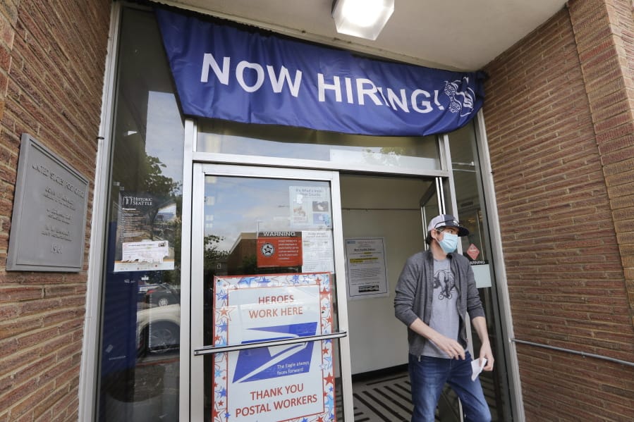 A customer walks out of a U.S. Post Office branch and under a banner advertising a job opening, in Seattle.