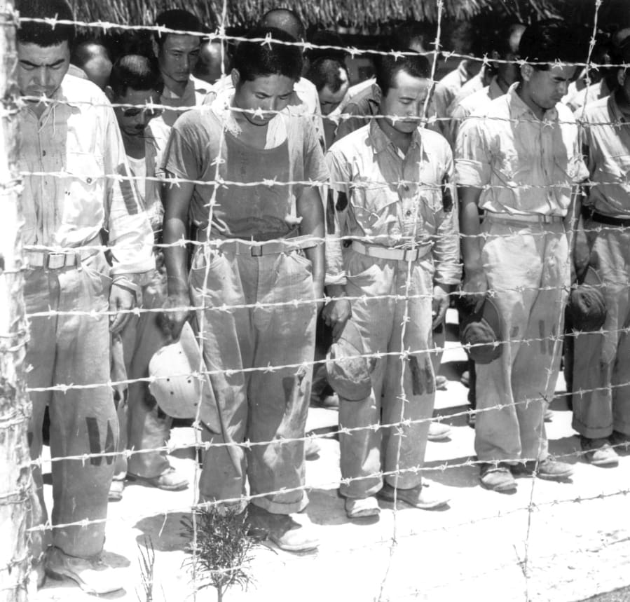 FILE - In this B/W file photo dated Aug. 15, 1945, Japanese prisoners of war at Guam, Mariana Islands, bow their heads as they hear Japanese Emperor Hirohito making the announcement of Japan&#039;s unconditional surrender.  Saturday Aug. 15, 2020, British Prime Minister Boris Johnson has paid tribute to surviving veterans of the multinational Allied campaign against Japan in World War II, which ended 75 years ago.